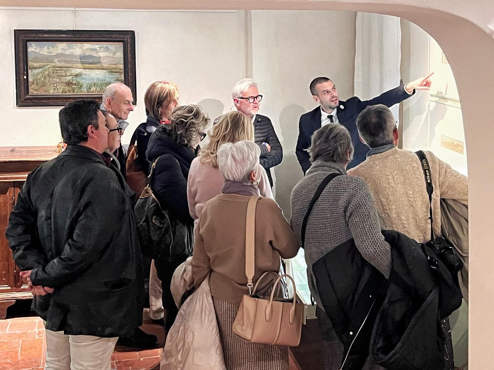 Gruppo di visitatori in visita guidata al Puccini Museum di Lucca nella sala dedicata a Giacomo Puccini, con pannelli espositivi e cimeli storici