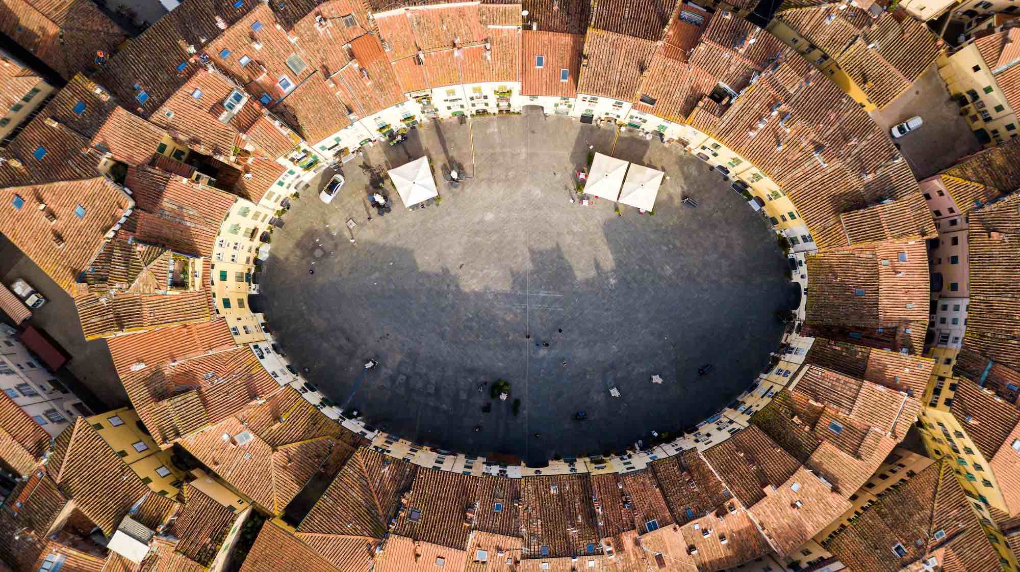 Aerial view of the Piazza dell'Anfiteatro in Lucca showing its elliptical shape surrounded by terracotta rooftops