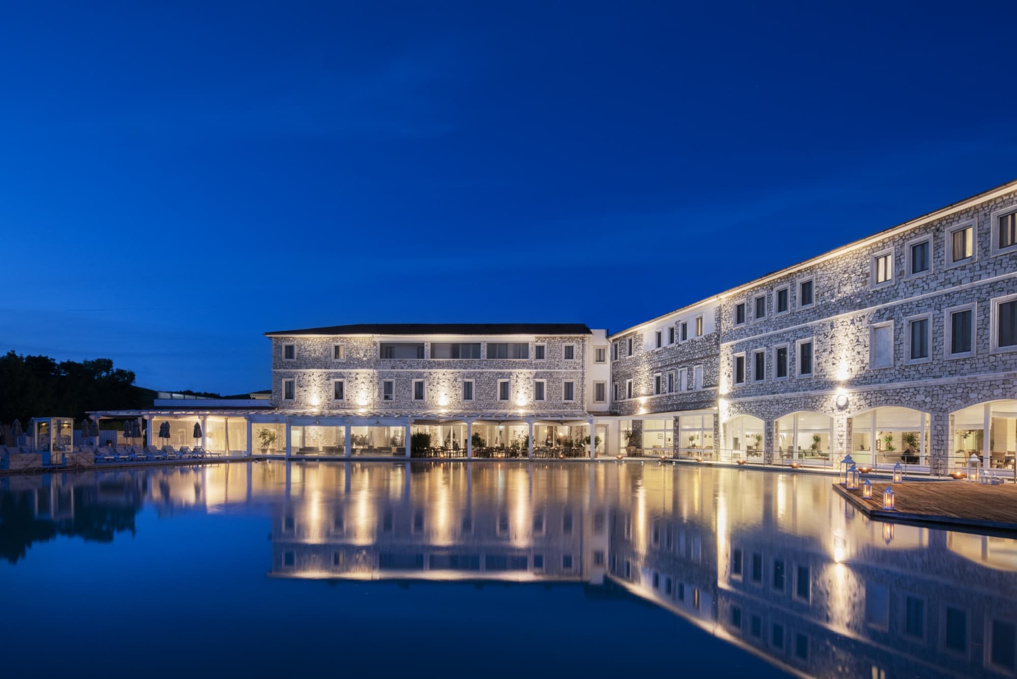 Saturnia Thermal Baths outdoor swimming pool lit up at night.