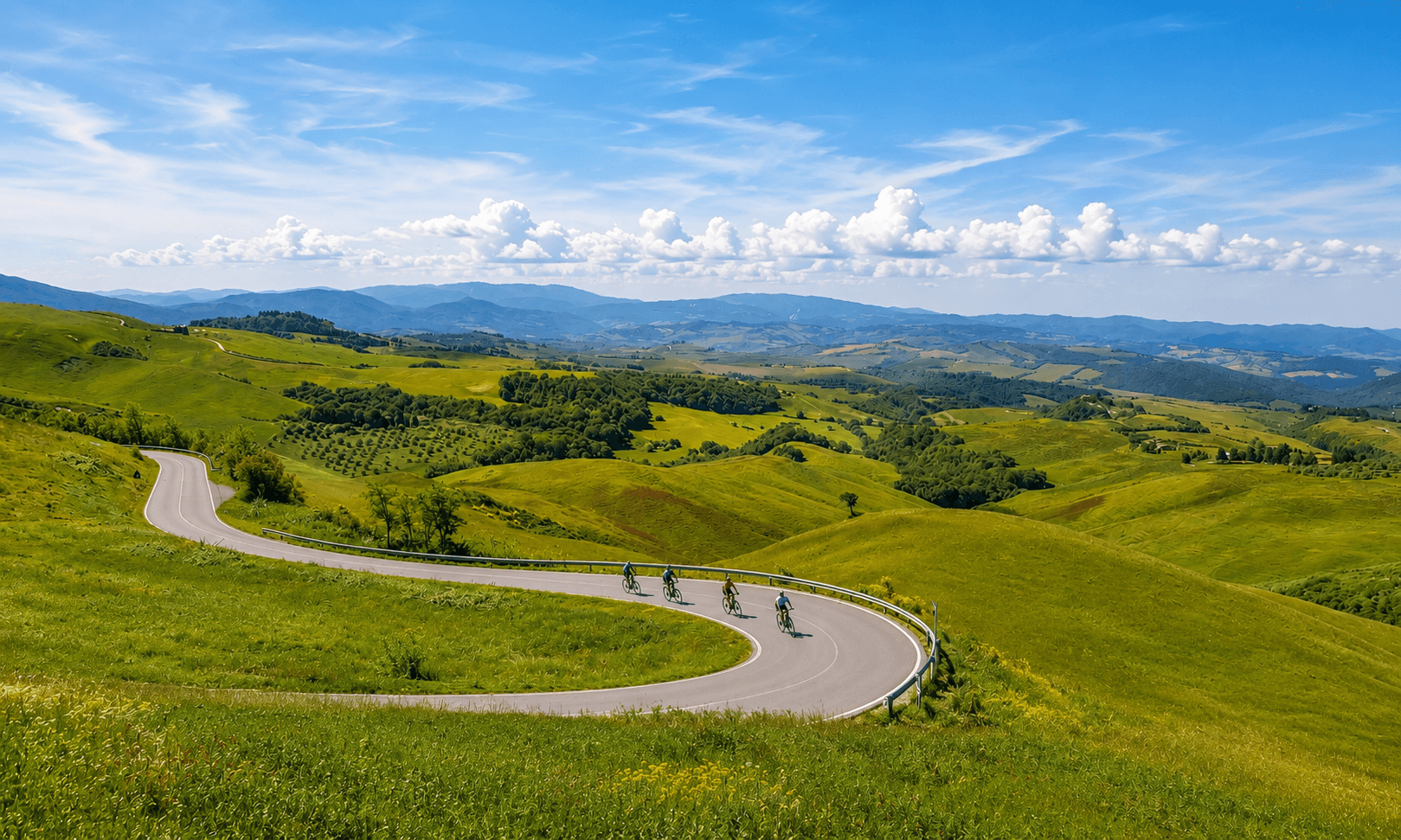 Ciclisti in bicicletta su una strada asfaltata tortuosa tra colline verdeggianti e boschi della Toscana sotto un cielo azzurro estivo
