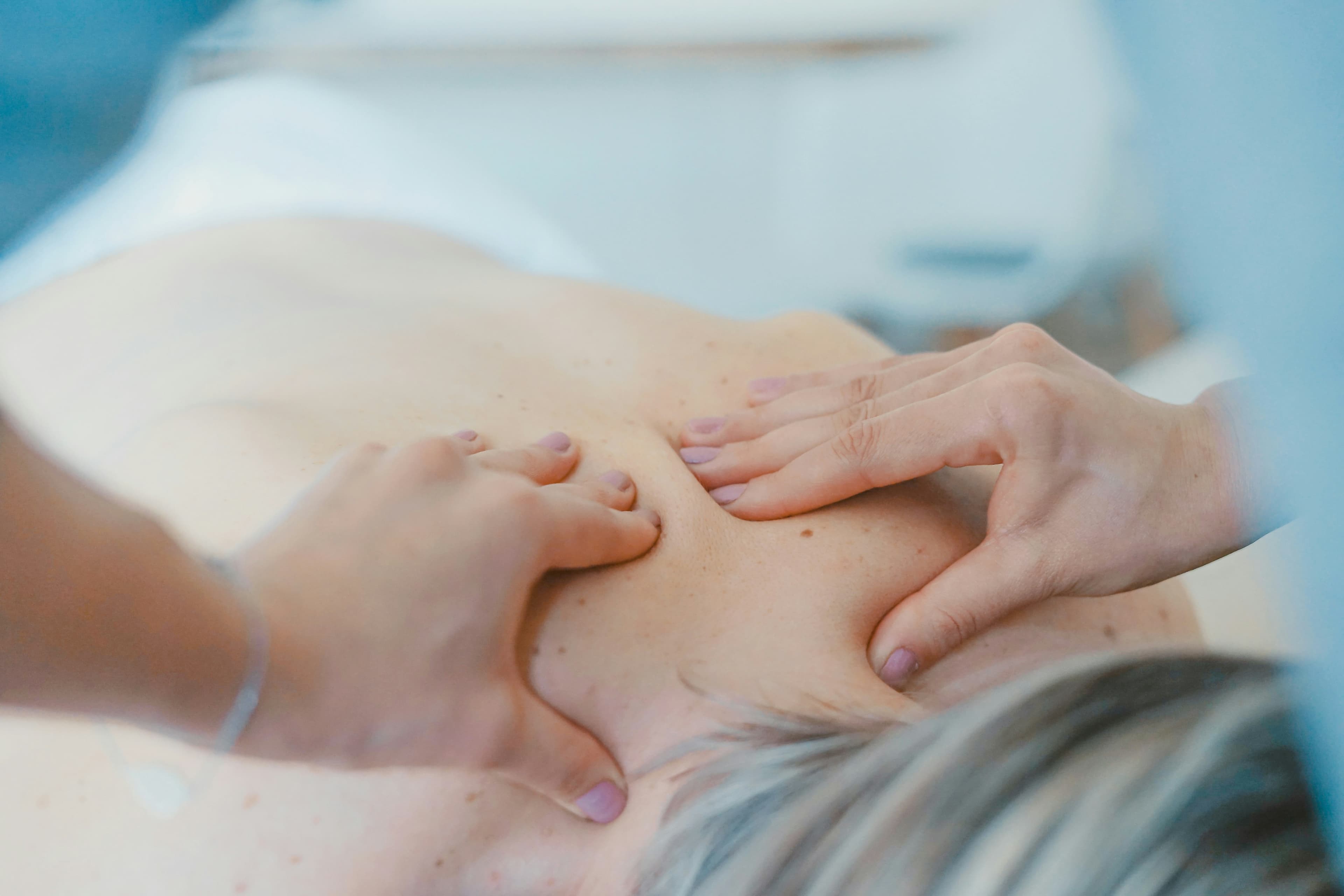 Massaggiatrice che esegue un massaggio rilassante sulla schiena di una persona distesa sul lettino da massaggio, servizio incluso nel pacchetto benessere Balance & Bliss