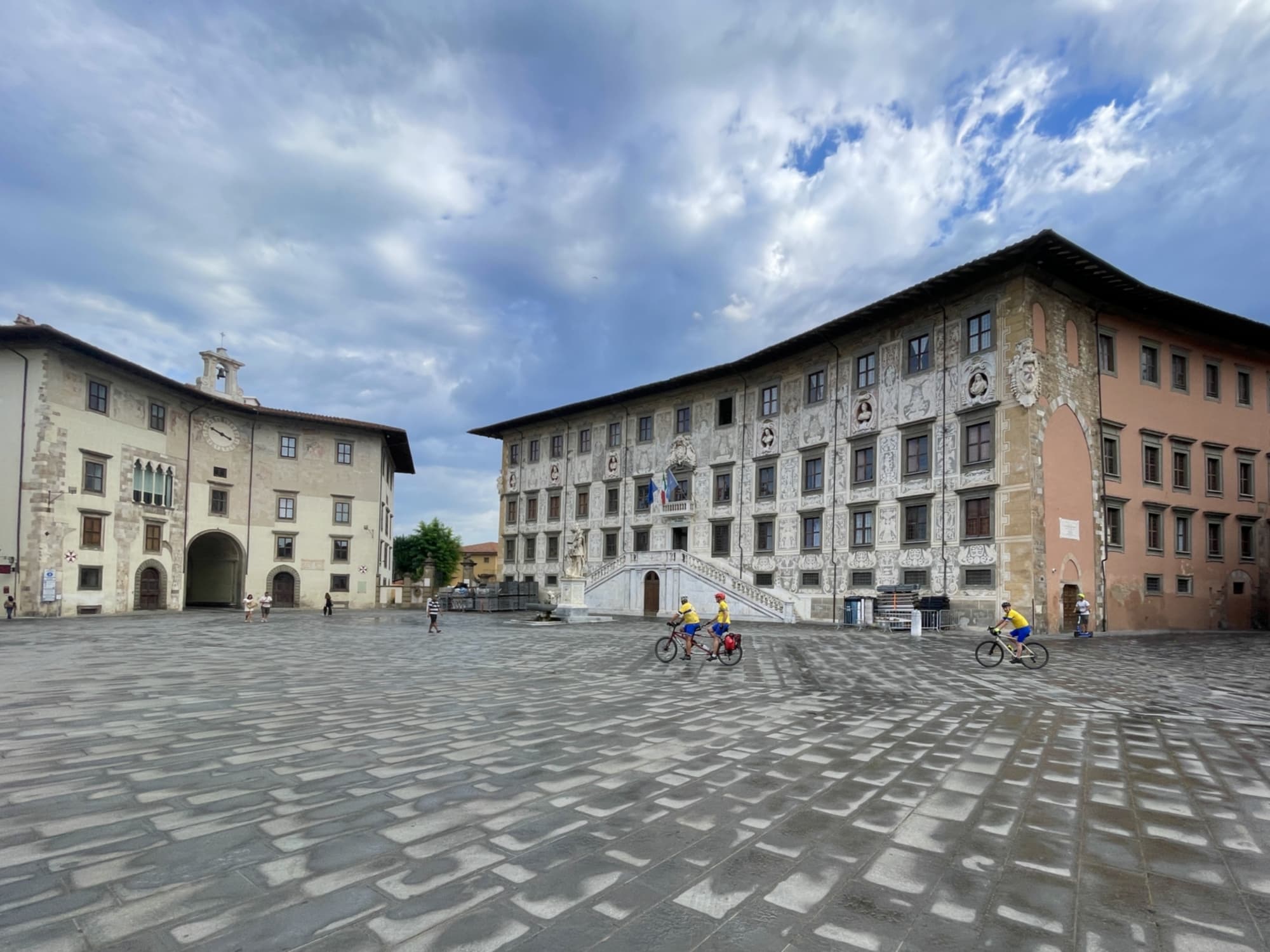 Veduta della Piazza dei Cavalieri a Pisa mentre transitano alcuni ciclisti.