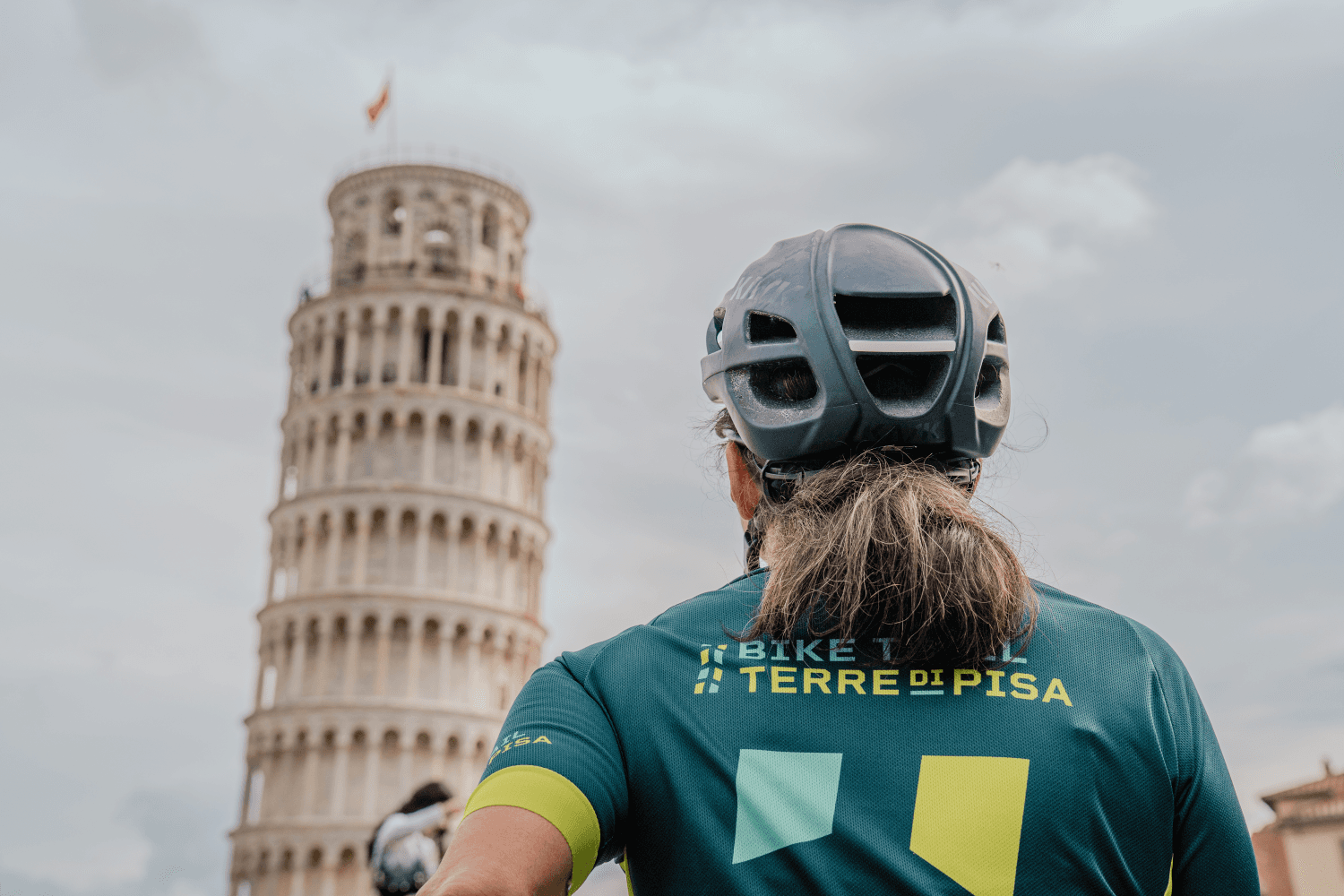Una ciclista guarda la Torre Pendente in Piazza dei Miracoli, punto di partenza ideale del percorso permanente Terre di Pisa Bike Trail