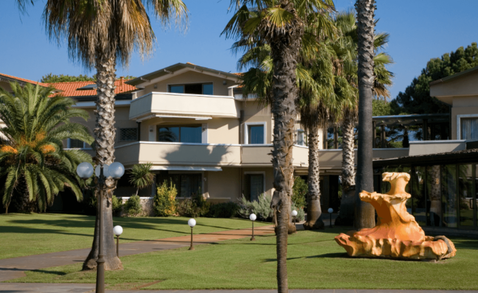The exterior facade of an elegant hotel or upscale residential building, reminiscent of a luxury resort or residence style, captured on a bright and sunny day.