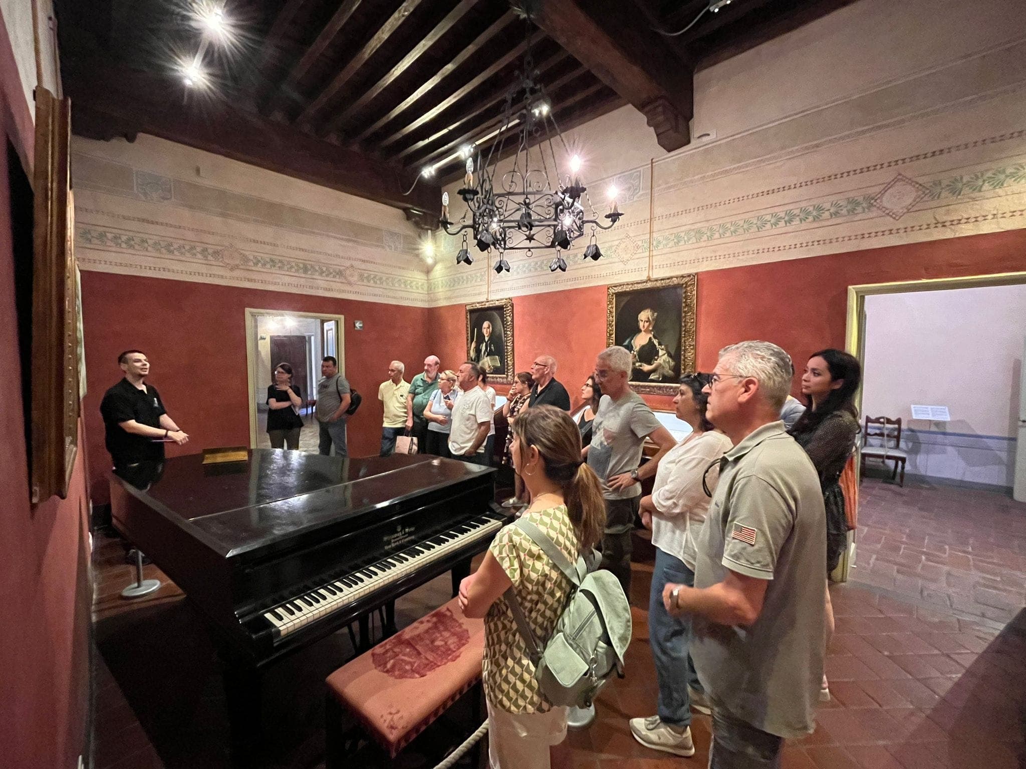 Guida turistica illustra a un gruppo di visitatori la sala con il pianoforte di Giacomo Puccini al Puccini Museum di Lucca