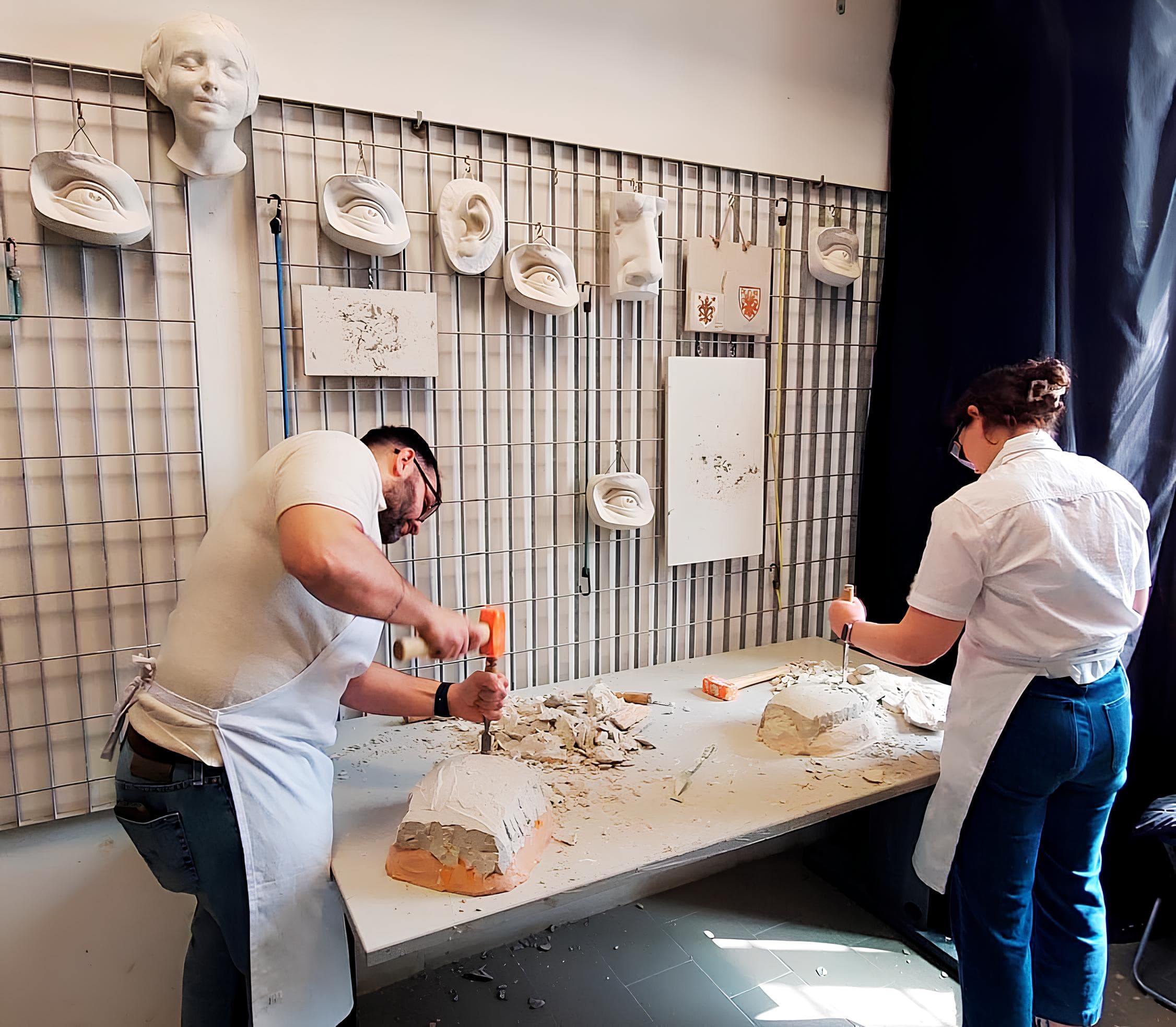 Mani al lavoro su scultura in gesso con strumenti tradizionali da scultore