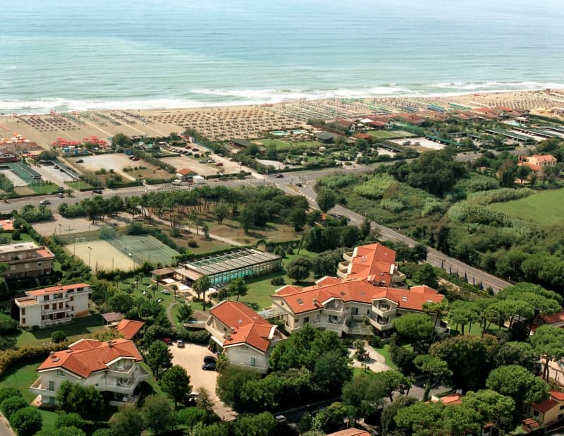 Aerial view of Hotel Villa Undulna with red roofs, tennis courts, and equipped beach in Cinquale Tuscany