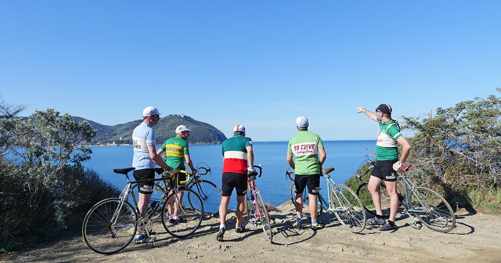 Partecipanti alla Ciclostorica 99 Curve con biciclette d'epoca davanti a un panorama sul mare