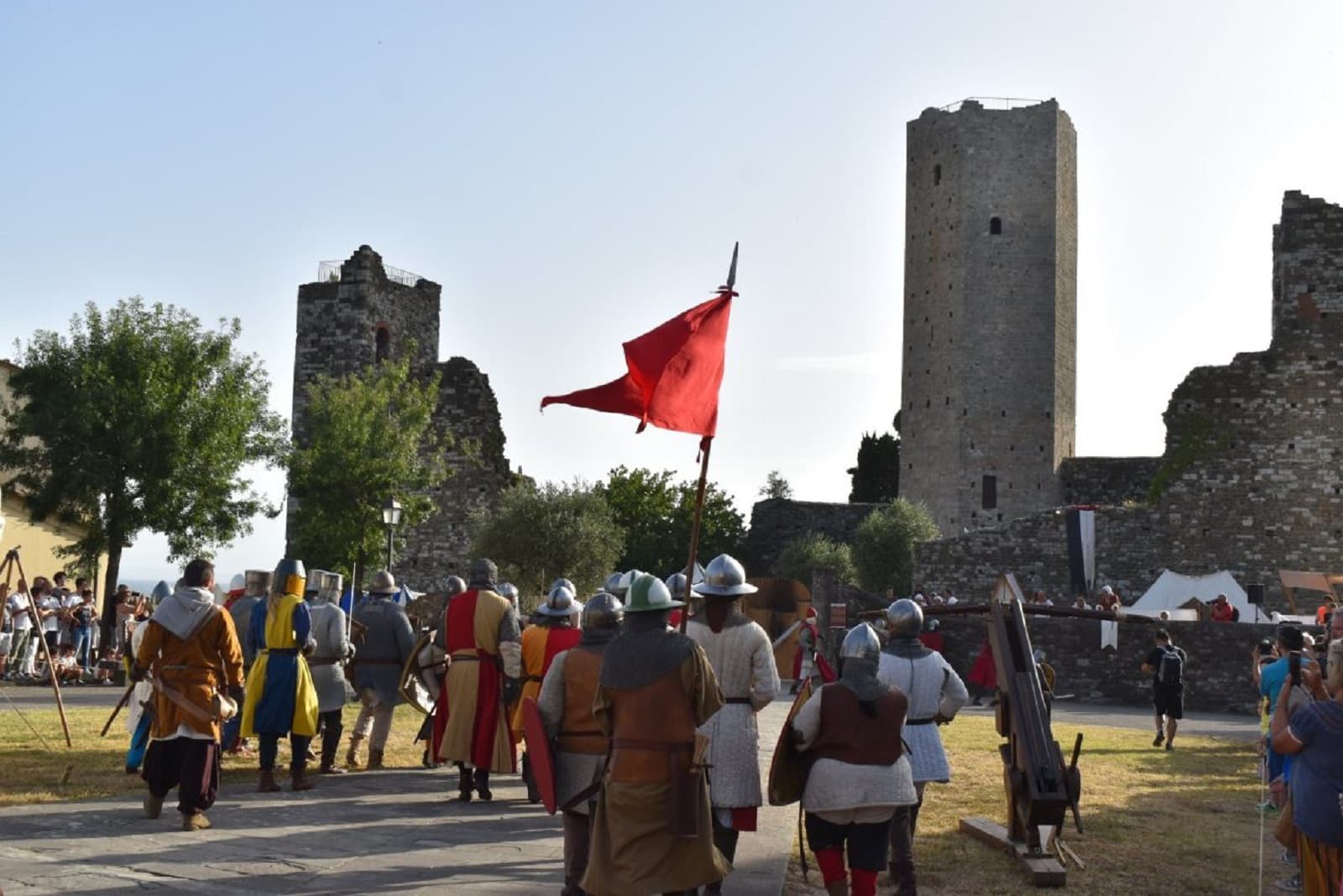 Figuranti in armatura e costume sfilano con una bandiera rossa davanti alla Rocca di Castrucci