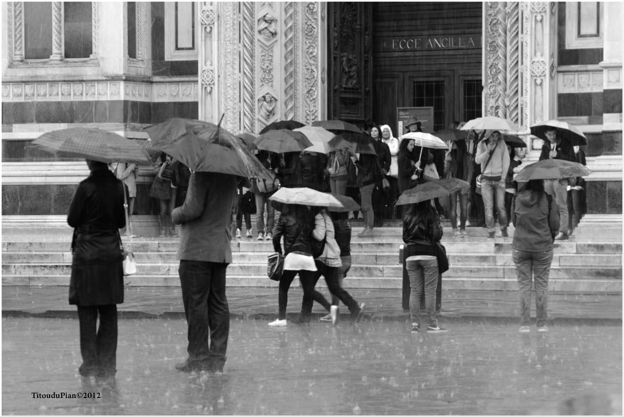 Una giornata piovosa a Firenze, in primo piano delle persone con l'ombrello aperto.