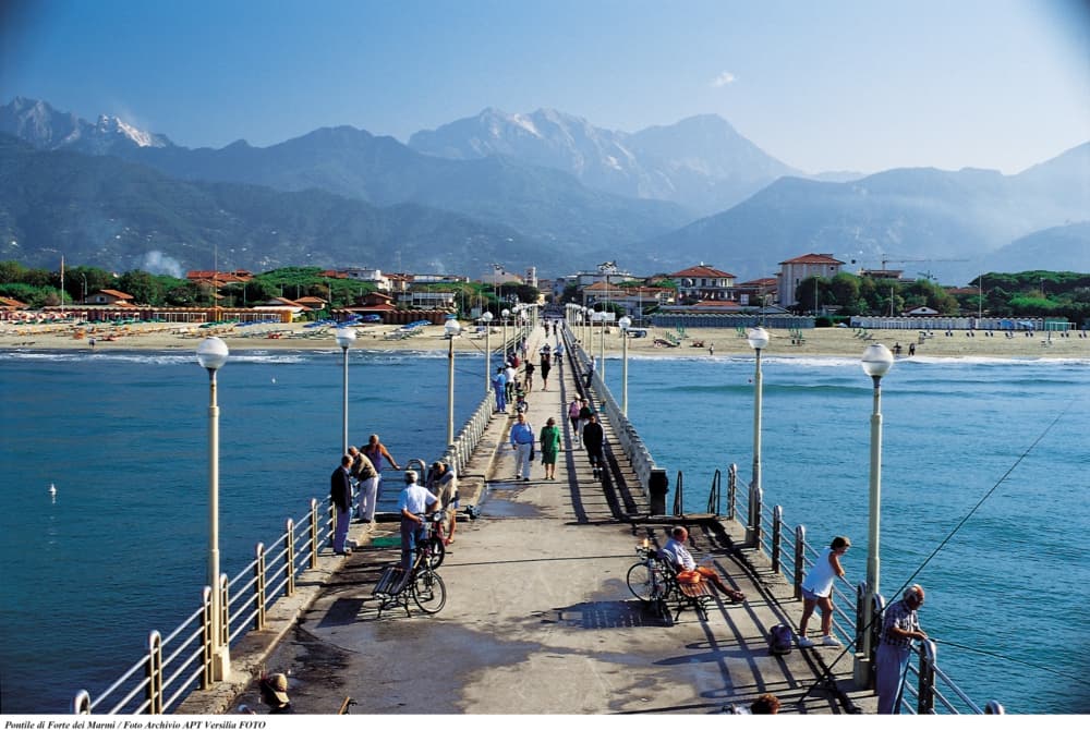Pontile di Forte dei Marmi, un simbolo della Versilia, con le Alpi Apuane sullo sfondo.