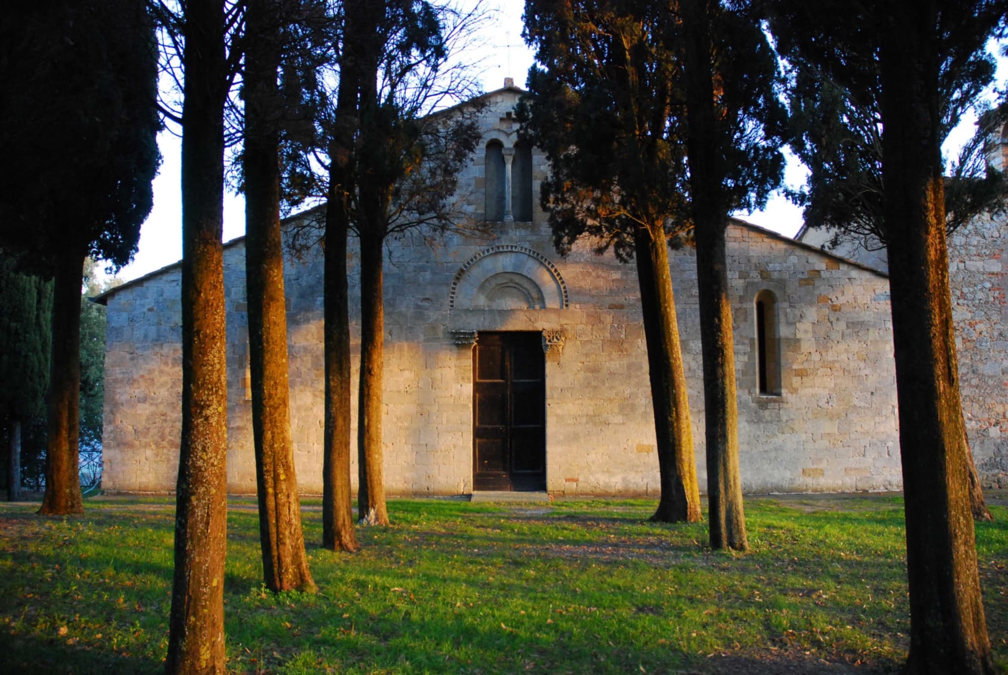 Facciata in pietra della Pieve di Cellole, esempio di architettura romanica immersa nella campagna toscana.