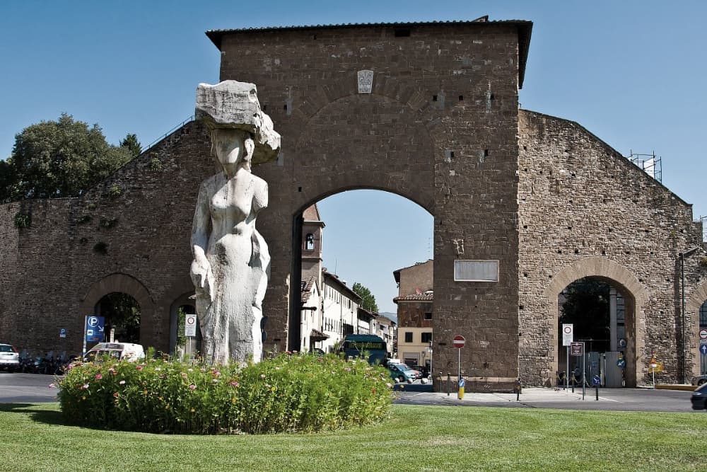 La statua che si trova davanti alla porta in primo piano, sullo sfondo Porta Romana