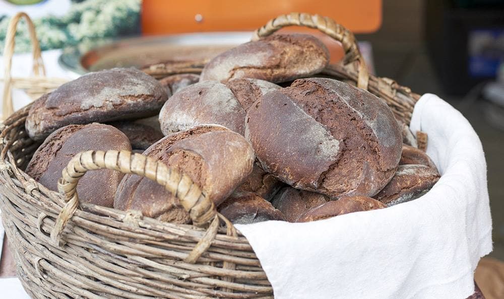Un panier en osier doublé d’un tissu blanc, rempli de pains Marocca di Casola