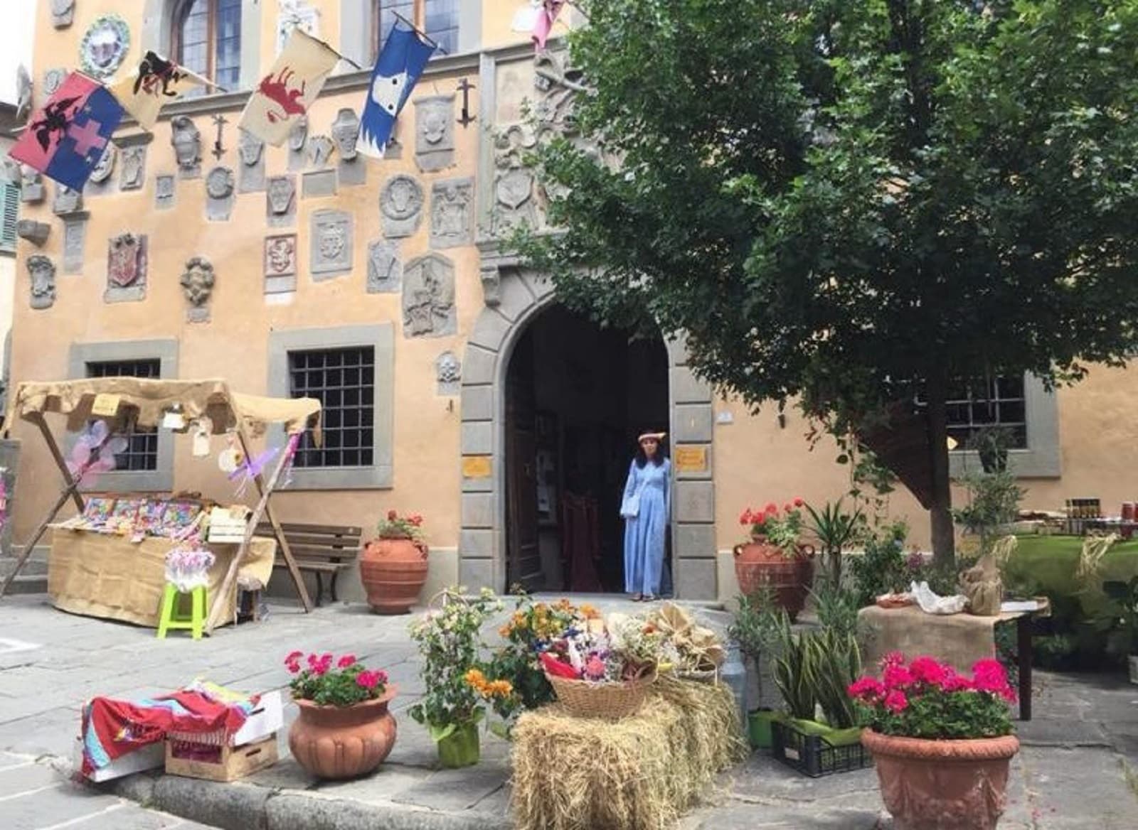 Allestimento di Cutigliano Medievale nel centro storico con una bancarella artigianale, decorazioni floreali e una figurante in abito d’epoca