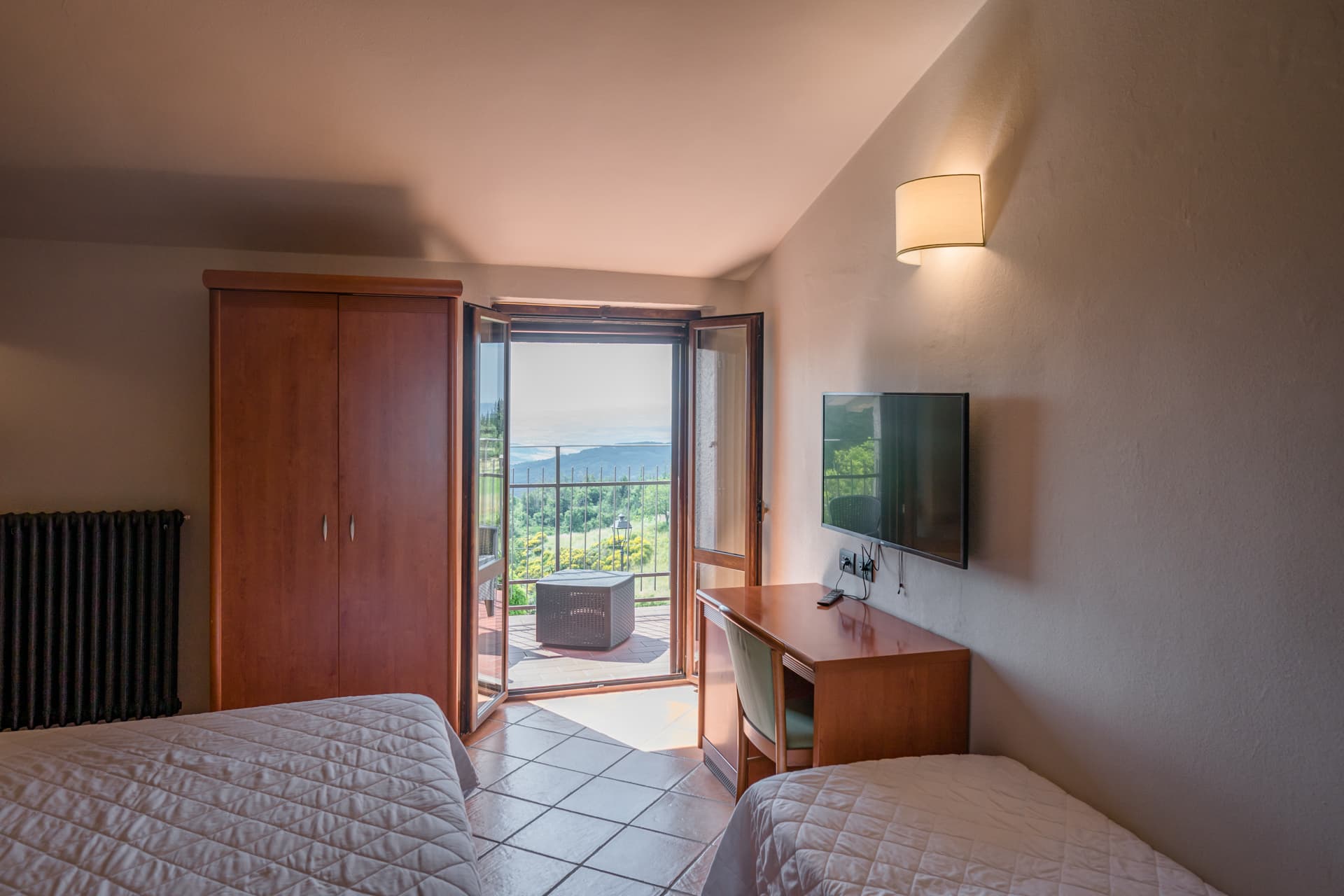 A twin bedroom with French doors leading onto a balcony offering panoramic views.