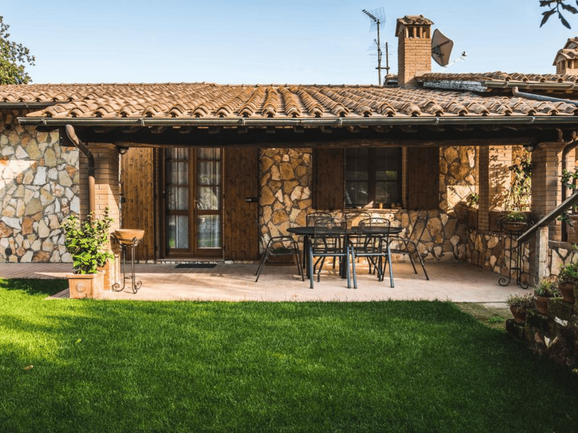 Lo spazio esterno attrezzato con tavoli e sedie e con giardino intorno alla struttura