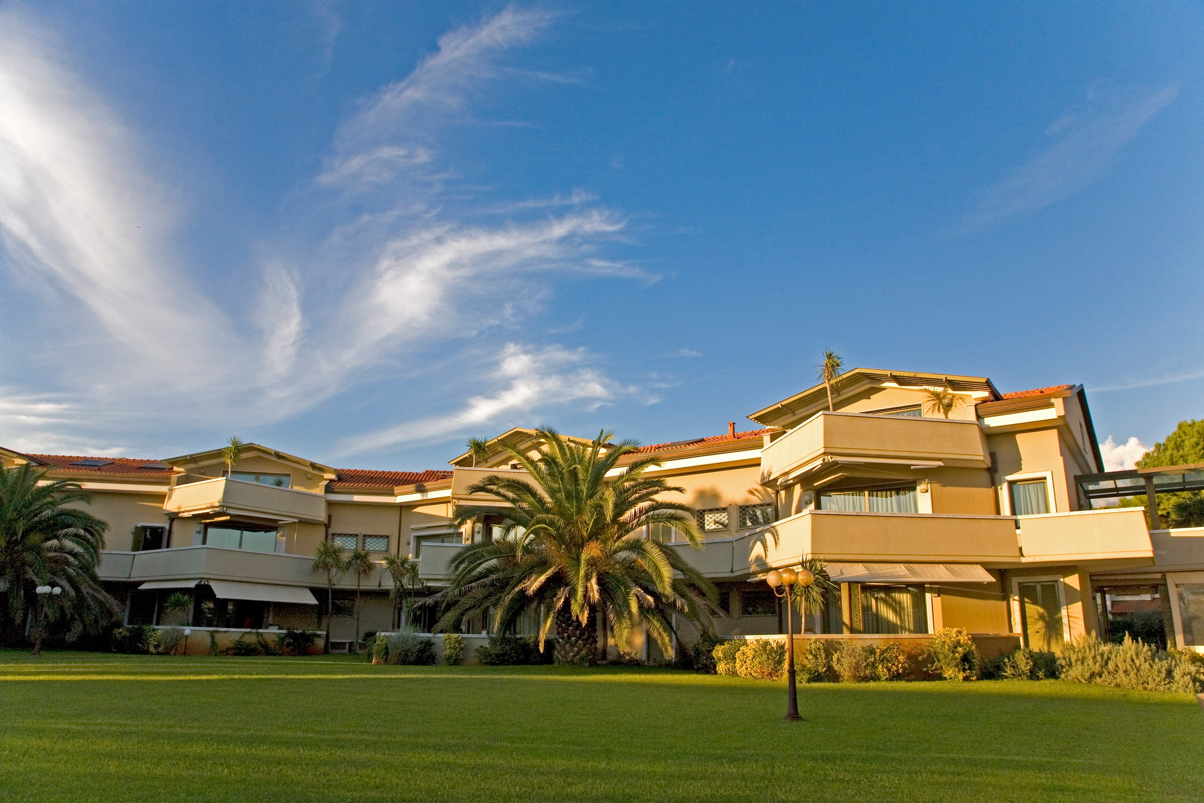 The exterior facade of an elegant hotel or upscale residential building, reminiscent of a luxury resort or residence style, captured on a bright and sunny day.