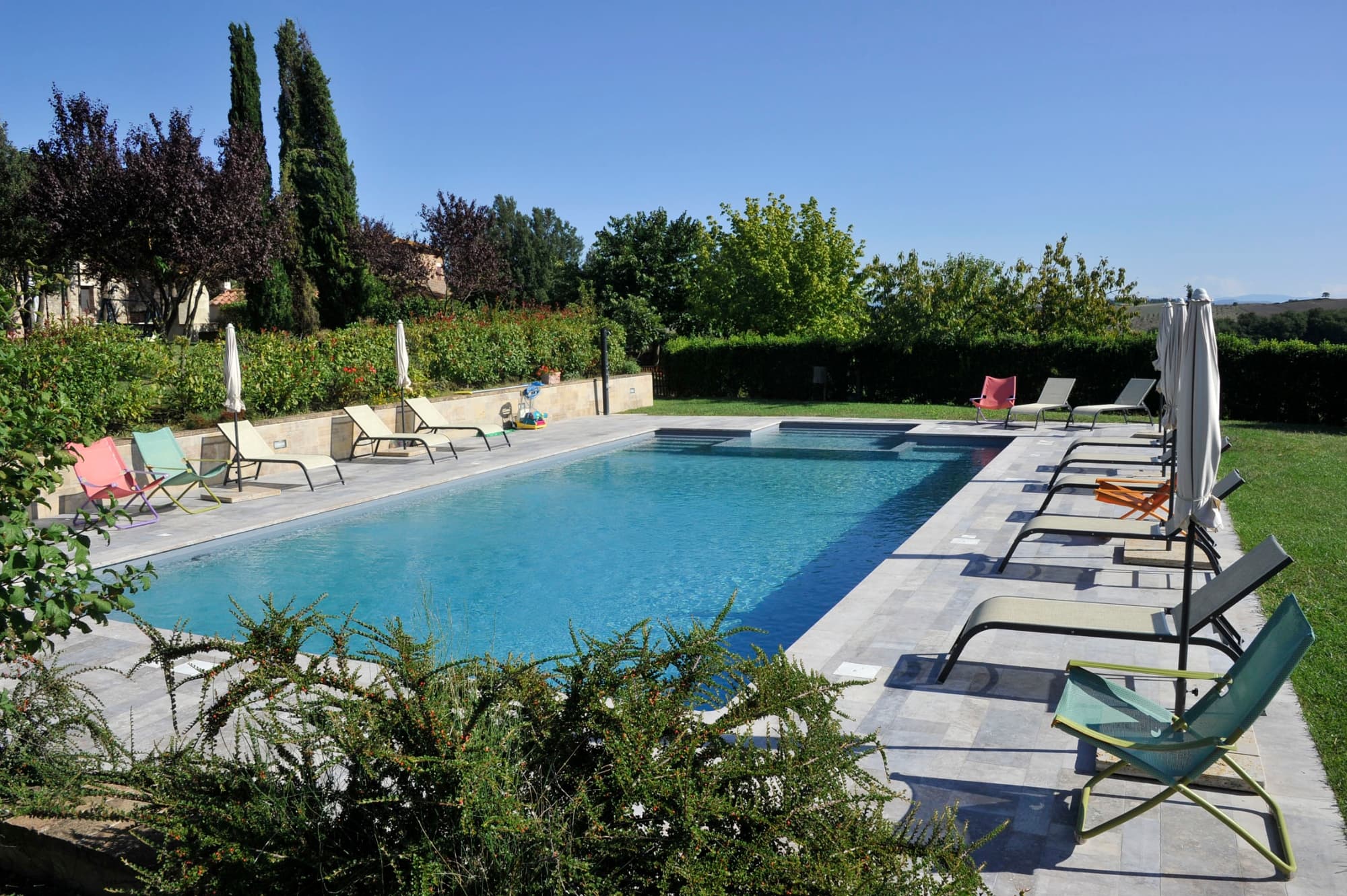 Piscina all'aperto dell'agriturismo Podere il Moro con lettini, ombrelloni e giardino circostante in Toscana