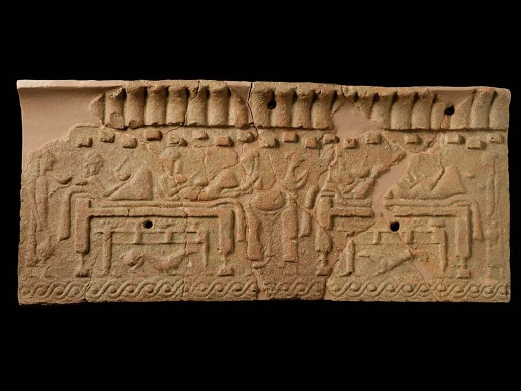 Stone slab with carvings depicting a banquet scene.