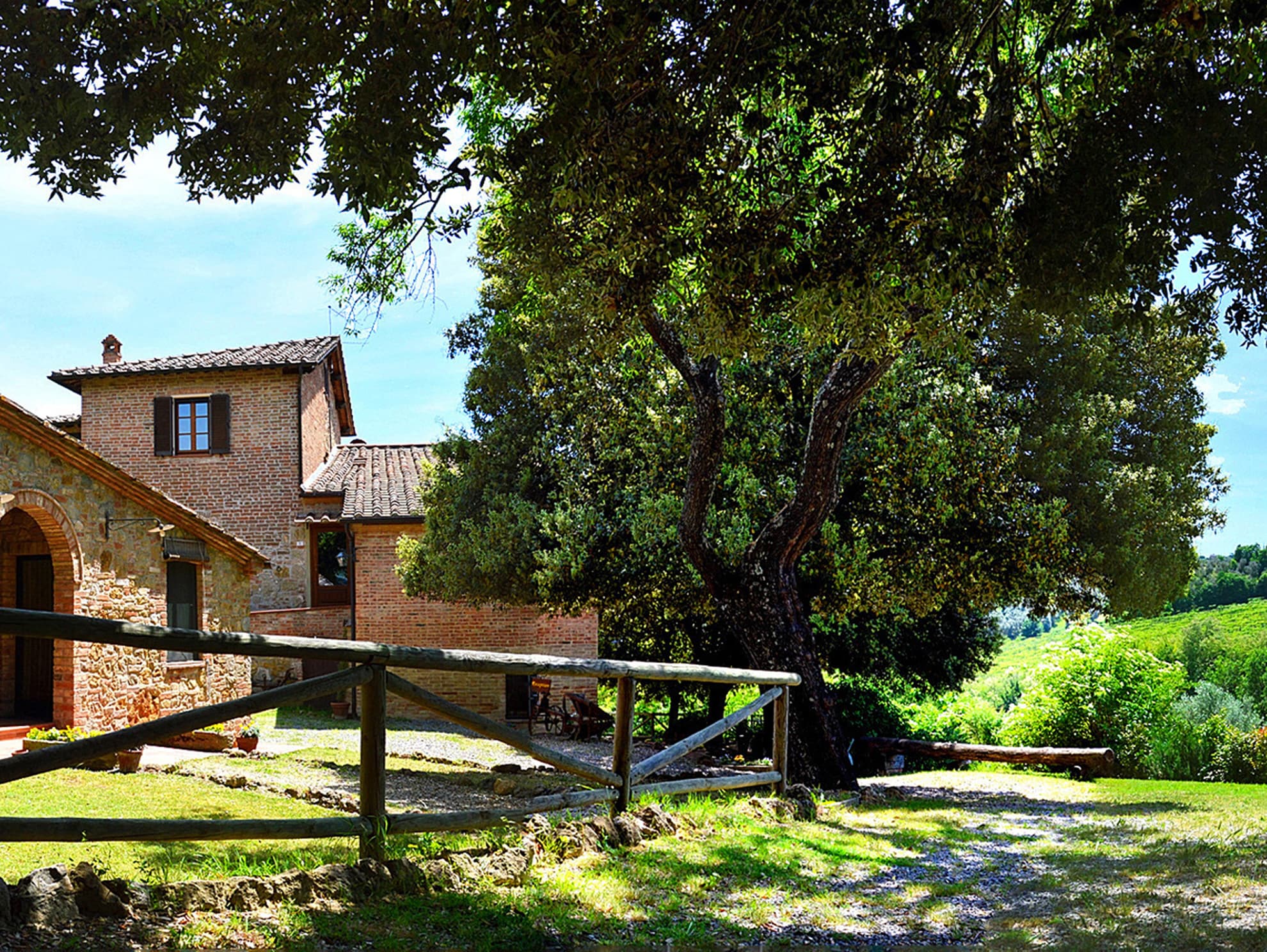 Esterno del casale in pietra circondato da alberi e campagna vicino a Montepulciano