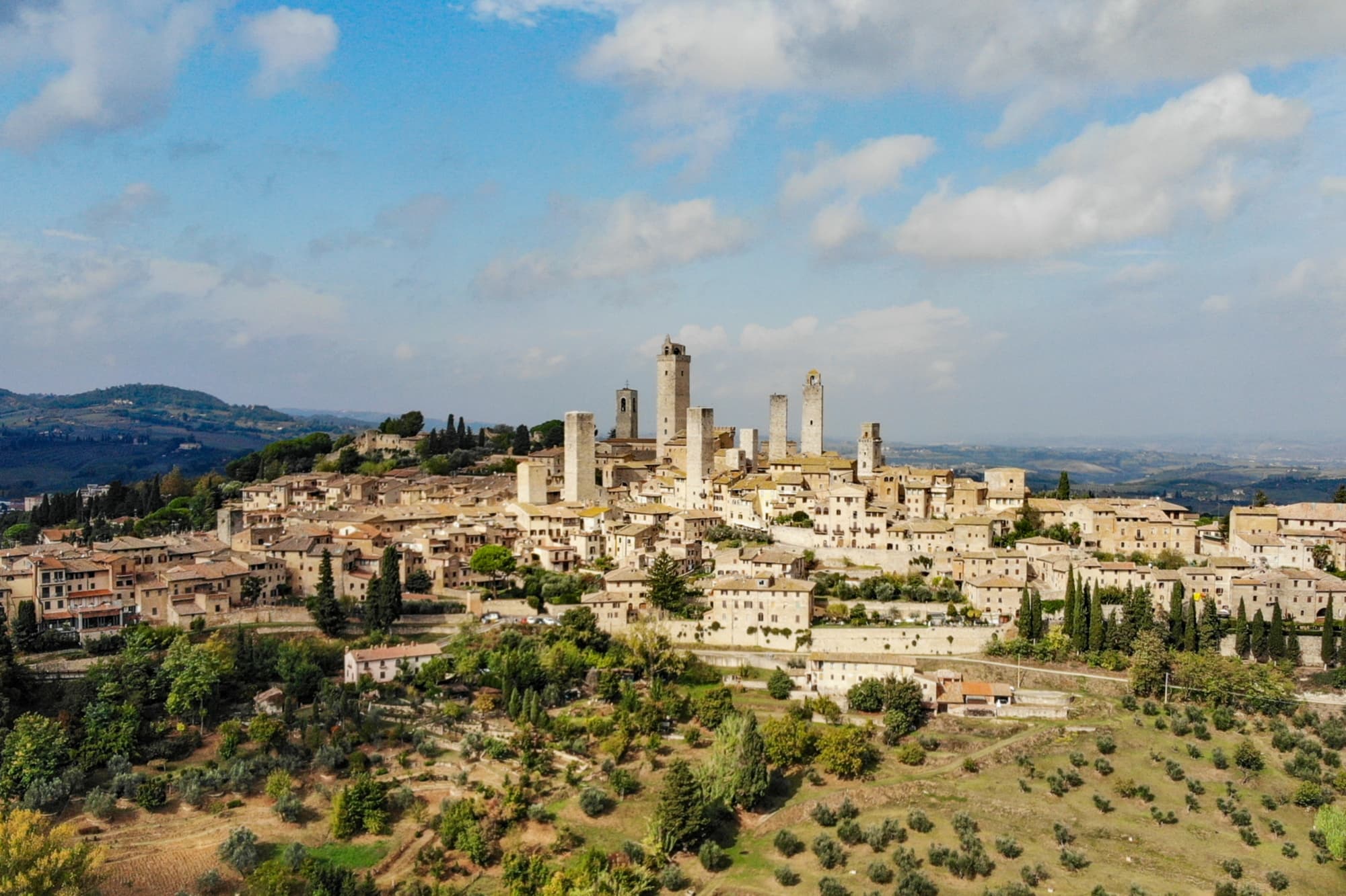 Panoramica su San Gimignano con le sue iconiche torri medievali che svettano tra le dolci colline toscane.