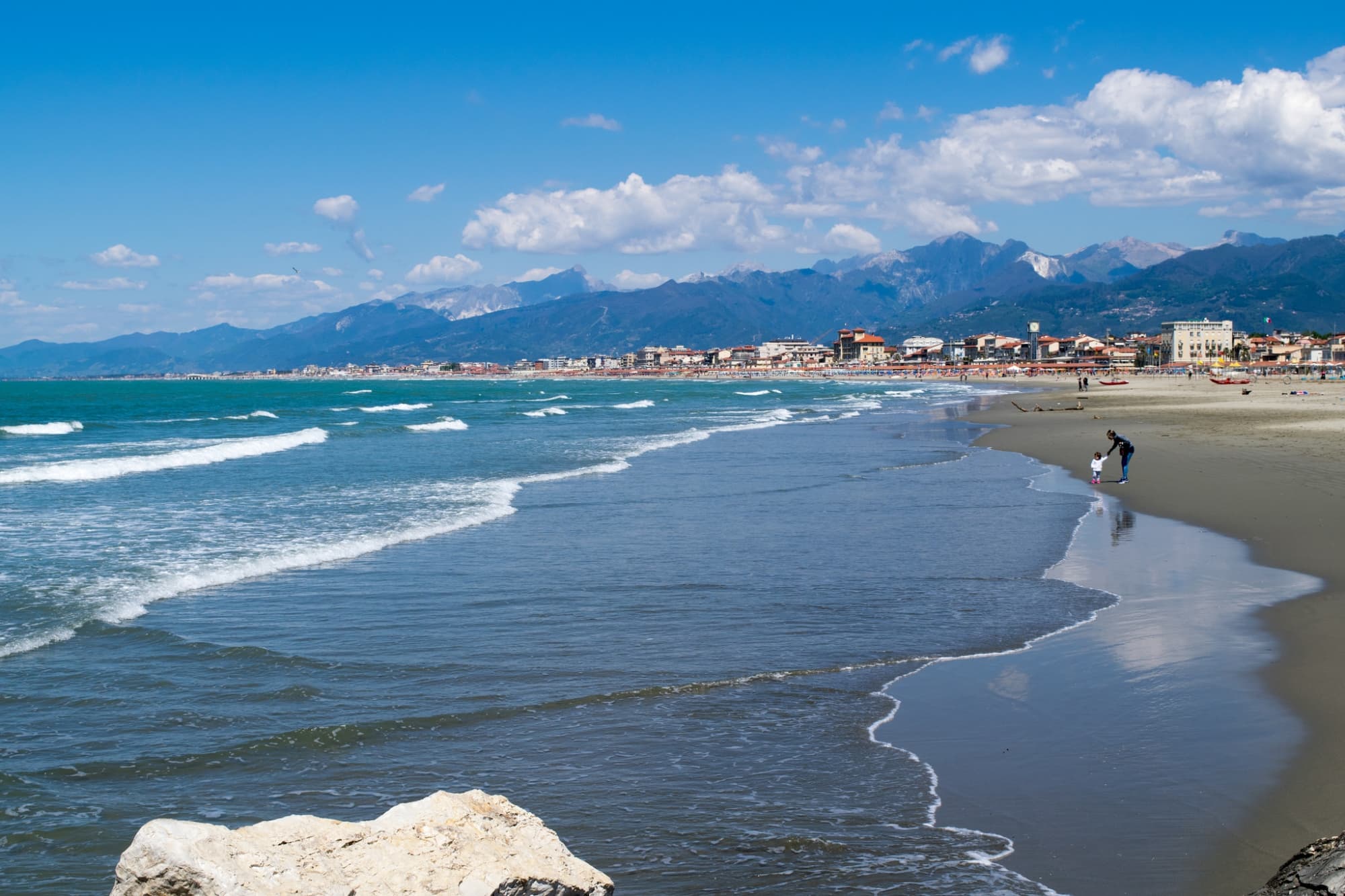 Mamma con bimba sulla spiaggia della Versilia con le Alpi Apuane sullo sfondo.